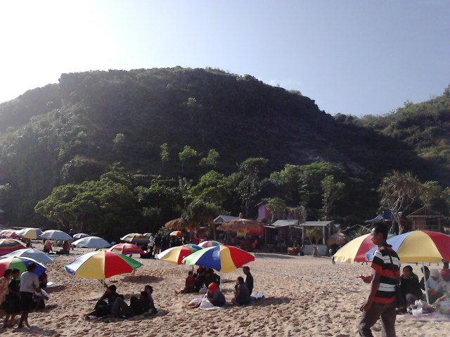Beberapa pengunjung berlindung di bawah bentangan langit yang biru cerah
