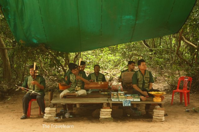 Cambodian traditional music player in front of Ta Prohm gate