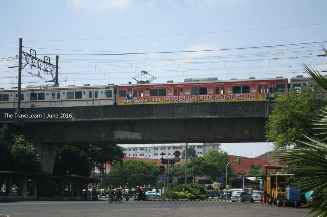 A commuter train is running on the elevated track near Monumen Nasional
